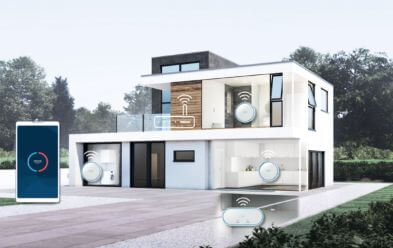 Moderne zweist�ckige Villa mit gro�en Fenstern und wei�er Fassade. Das Bild zeigt Symbole von smarten Haushaltsger�ten, die mit dem Haus vernetzt sind. Auf der linken Seite ist ein Smartphone abgebildet, das die Vernetzung mit smarten Ger�ten darstellt. Im Hintergrund ist ein Garten mit B�umen zu sehen.